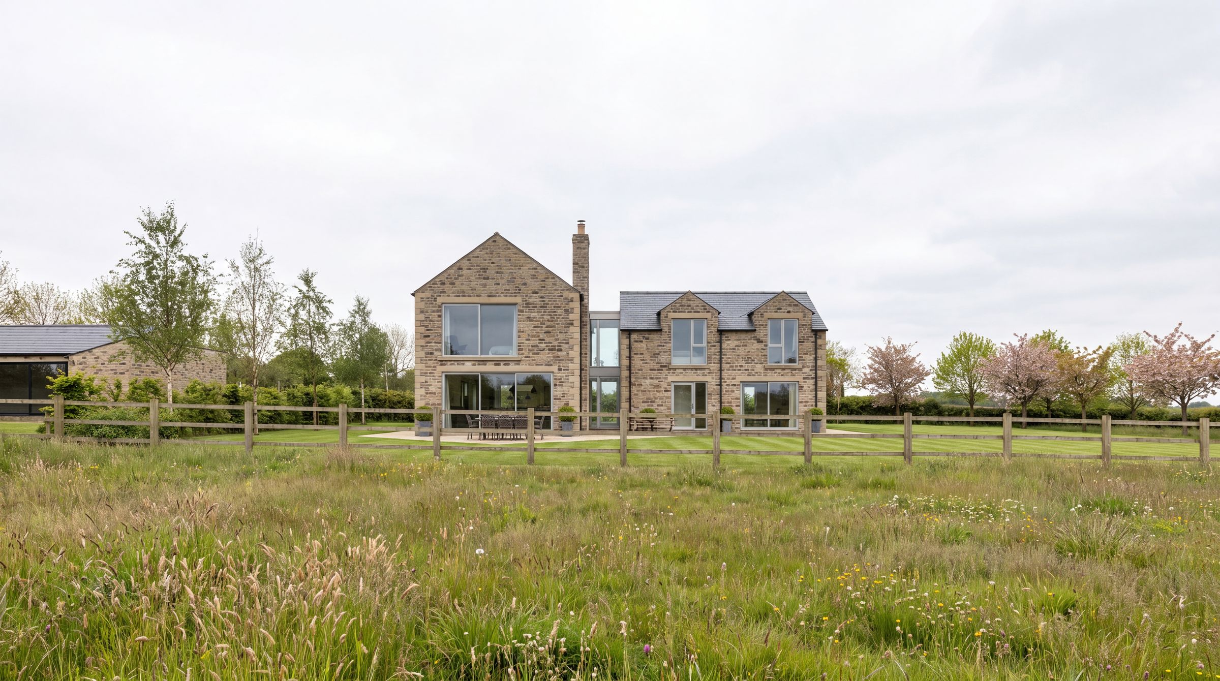 Rear elevation and full height glazing at Birkland Farm, seen across the meadow